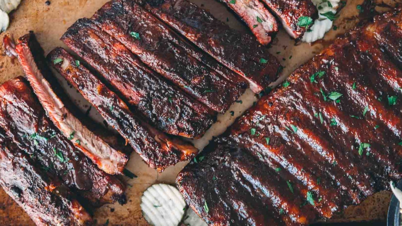 Smoked pork spare ribs with a glossy glaze stacked on a tray.