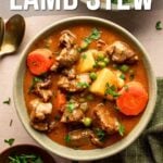 A bowl of Dutch oven lamb stew with carrots, potatoes, and peas, garnished with parsley, next to a green cloth, fresh herbs, and two spoons. Text reads: “How to make Dutch oven lamb stew.”.