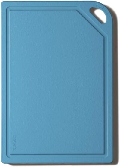 A rectangular blue cutting board with a slightly angled corner and a cut-out handle on the top right side.