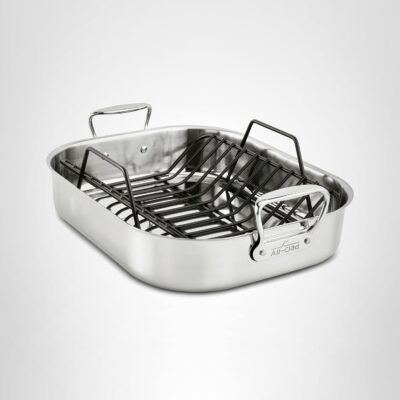 A stainless steel roasting pan with two handles and a removable black metal rack, perfect for learning how to carve a prime rib, shown on a plain white background.