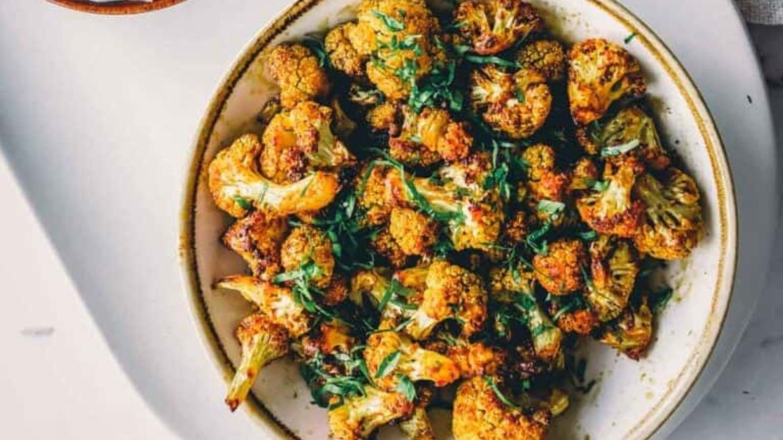Air fryer cauliflower browned and crispy with charred edges on a sheet.