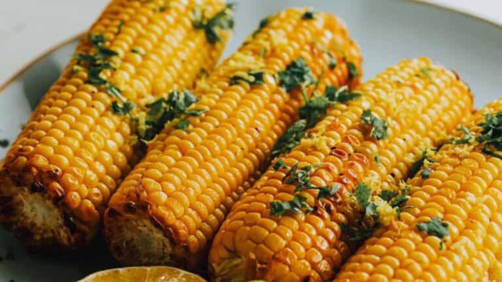 Air fryer corn on the cob with lightly charred kernels brushed with butter.