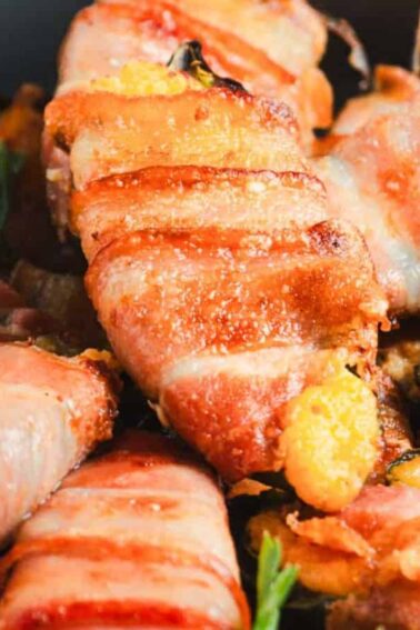 Bacon-wrapped jalapeño poppers arranged in a dish, garnished with fresh parsley.