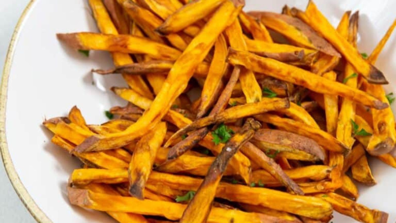 Air fryer sweet potato fries crisped golden with seasoning sprinkled across.