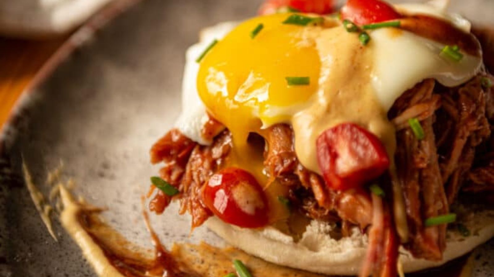 Eggs Benedict topped with pulled pork and smoked hollandaise sauce over toasted muffins.
