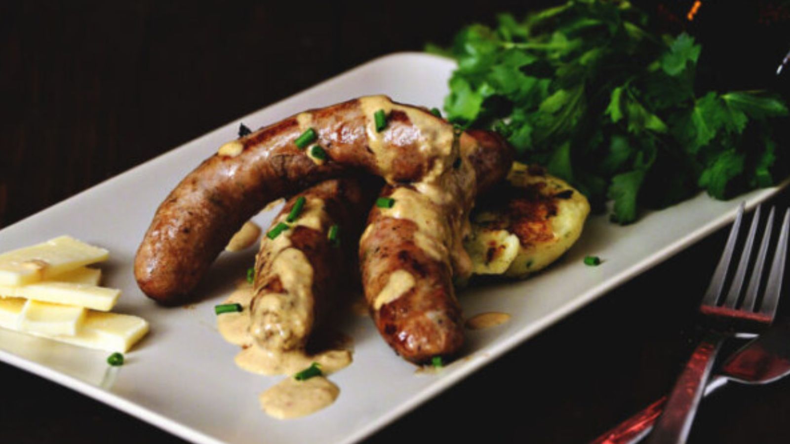 Sausages and mashed potatoes served with rich brown gravy poured over the entire plate.