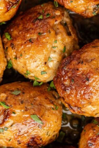 Close-up of cooked meatballs garnished with chopped herbs, showing a browned, crispy exterior.