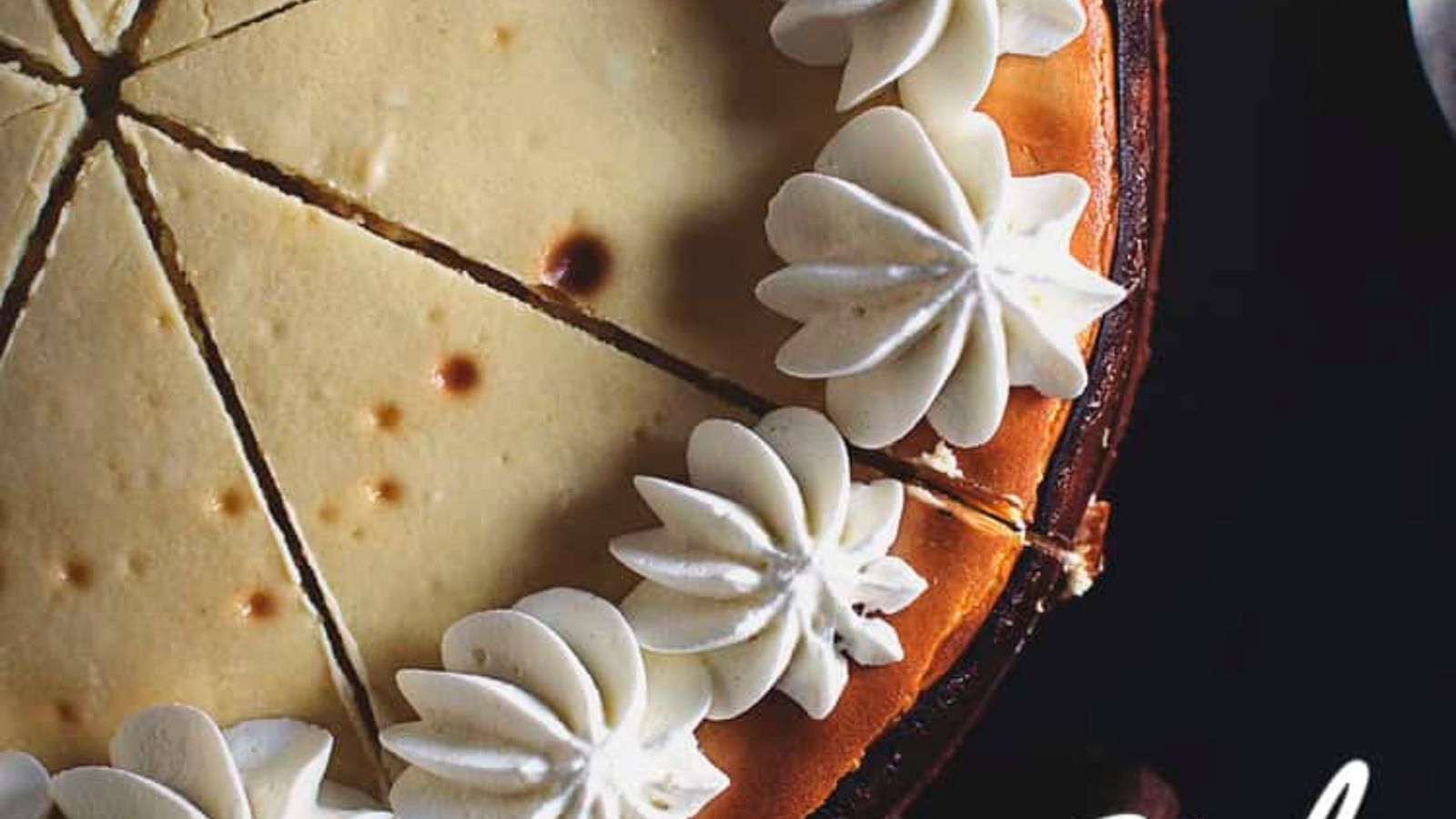 Overhead view of a sliced cheesecake topped with piped whipped cream around the edge.