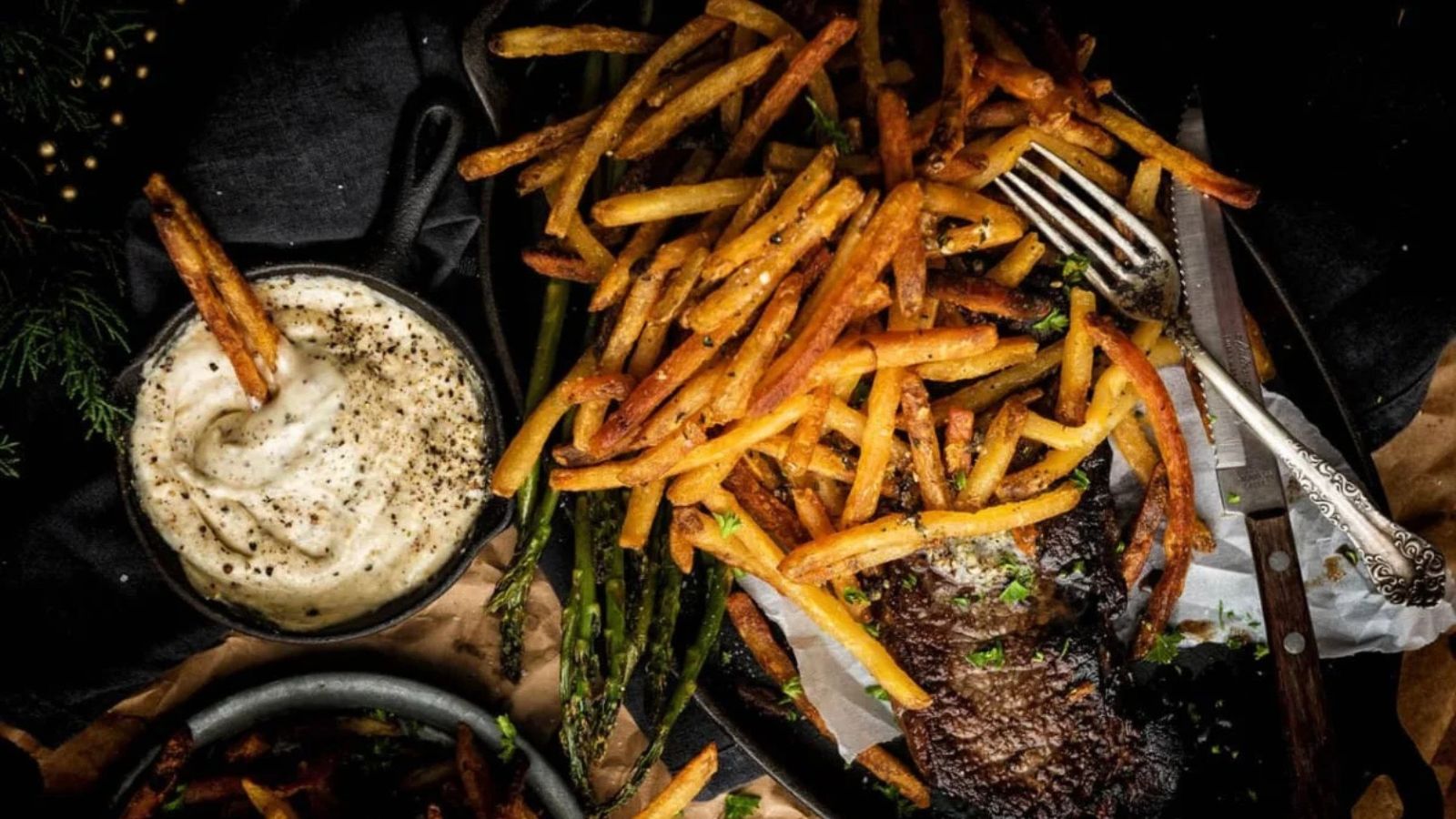 Duck fat French fries golden and crisp served in a bowl with herbs sprinkled.