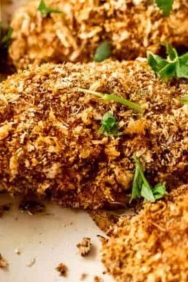 Breaded chicken breasts on a baking sheet, garnished with fresh parsley and lemon wedges, with a small dish of dipping sauceโperfect for festive gatherings and inspired by classic Christmas chicken recipes.