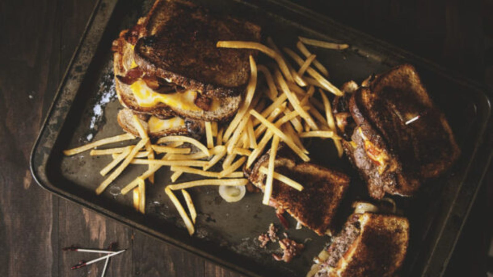 Burger grilled with melted cheese dripping down sides.