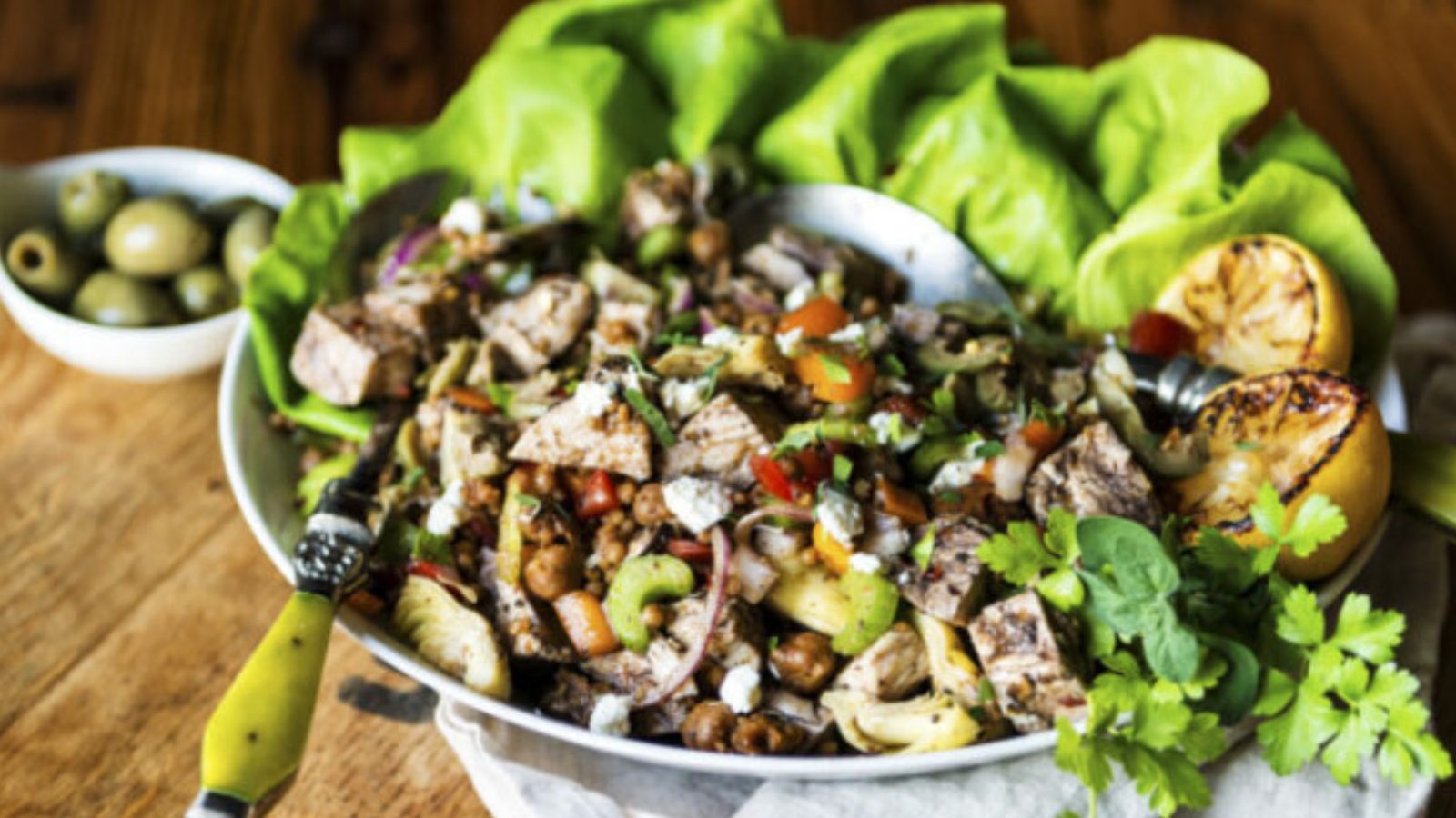 Salad topped with grilled chicken and Mediterranean vegetables with vinaigrette drizzle.