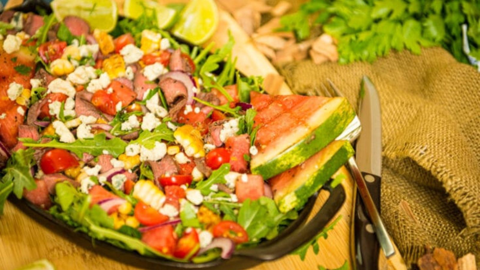 Salad topped with slices of grilled flat iron steak and fresh greens.