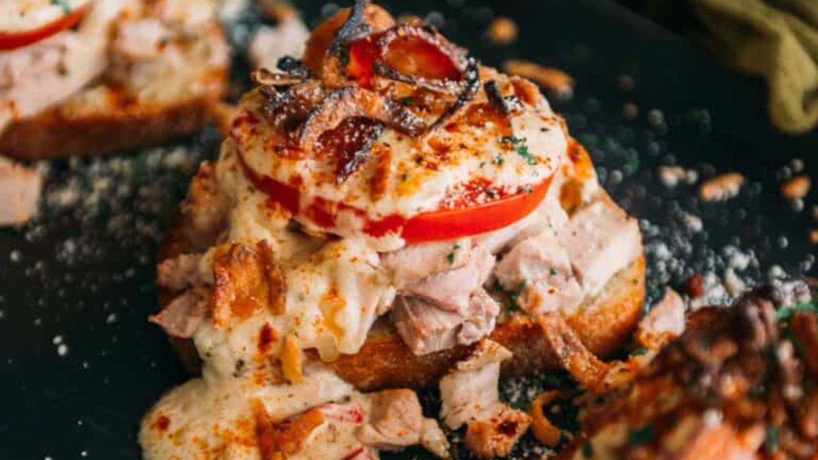 Hot Brown sandwich topped with turkey, sauce, and bacon.