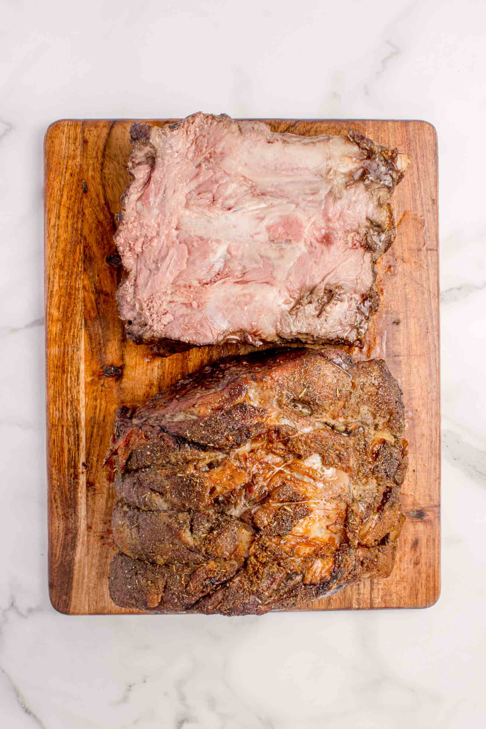A cooked prime rib roast with bones sitting next to the roast to show the ease of removing.