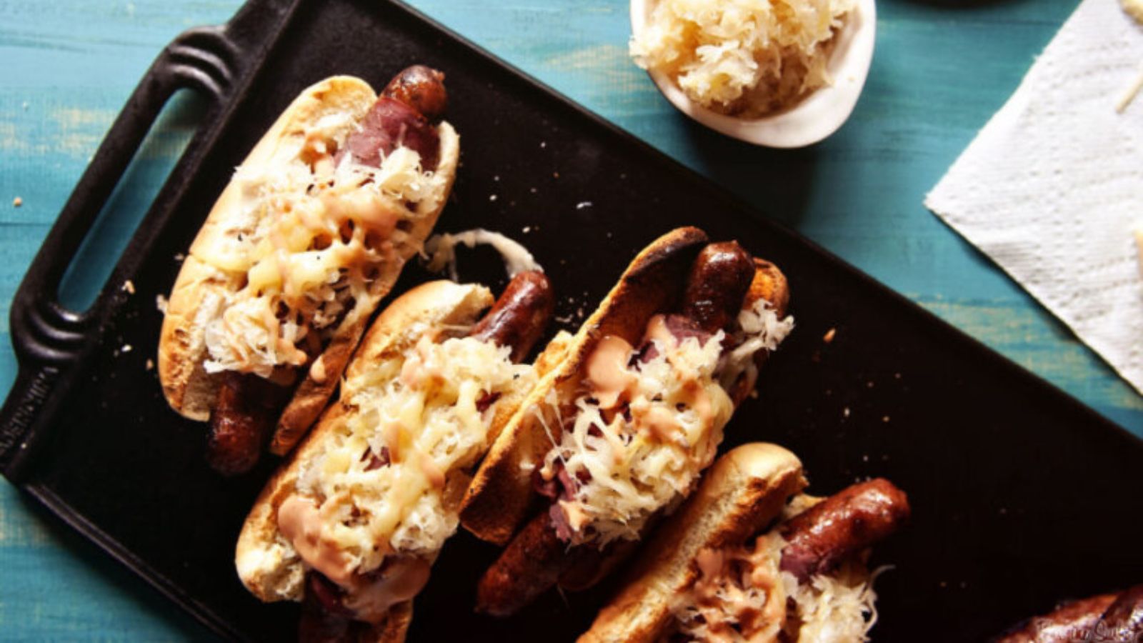 Hot dogs topped with Reuben fixings including sauerkraut.