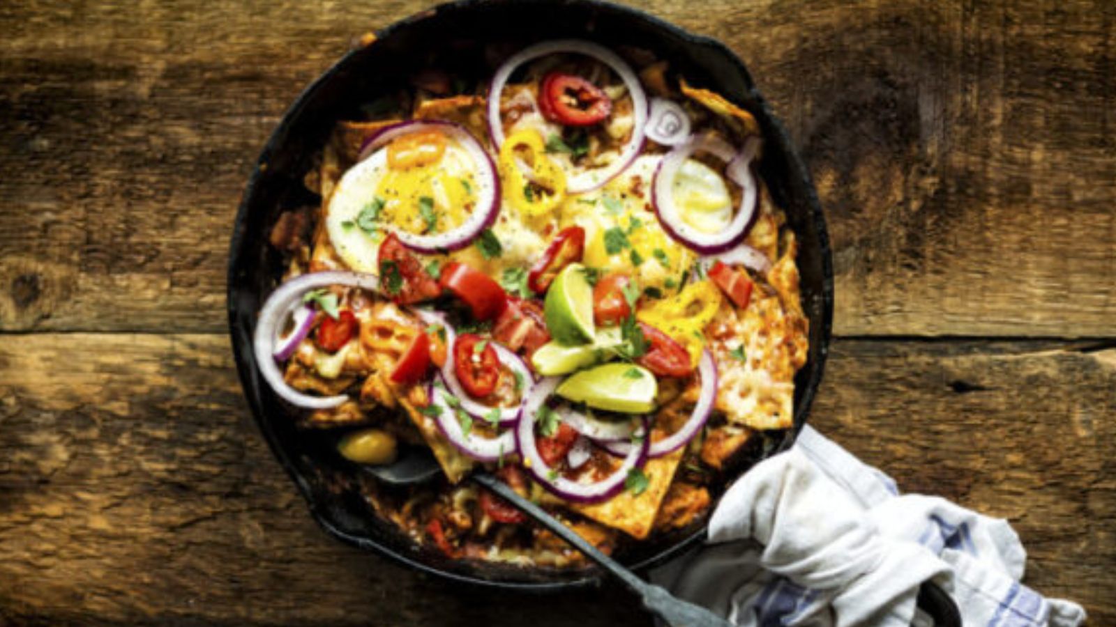 Chilaquiles topped with smoked chicken pieces layered over crisp tortillas and green sauce.
