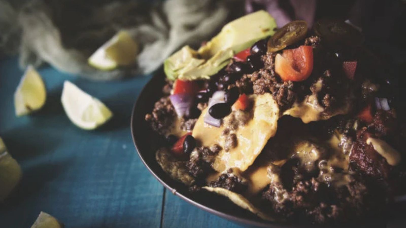 Nacho bowl layered with taco meat, beans, cheese, and toppings.