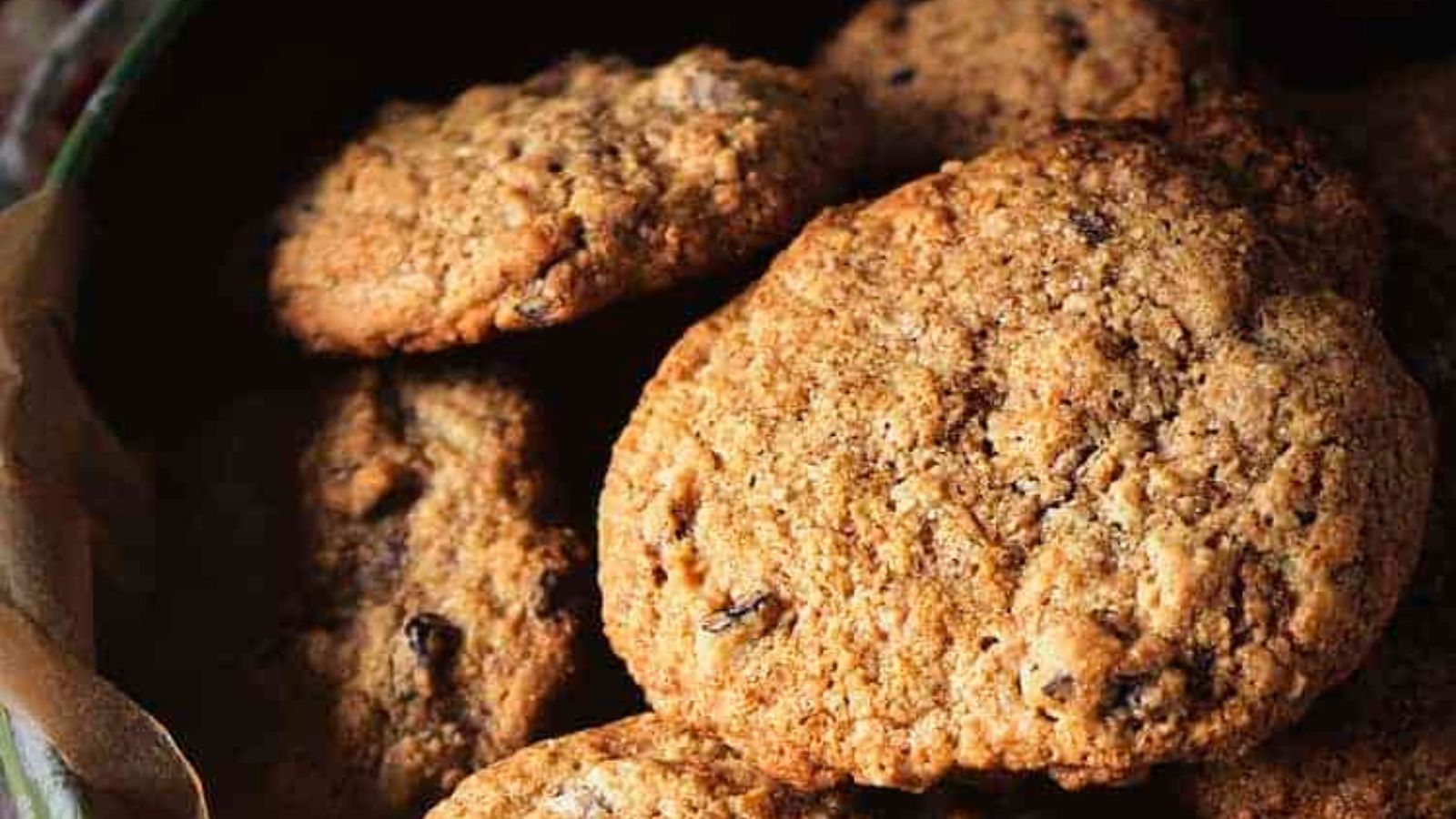 A close-up view of several golden-brown cookies with a slightly crumbly texture and visible bits of chocolate or nuts.