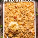 A baking dish filled with lobster mac and cheese topped with breadcrumbs, with a spoon lifting a serving; recipe information displayed above and below the dish.