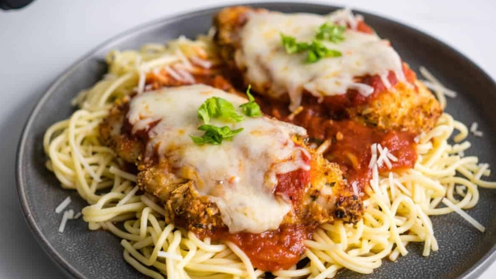 Pieces of chicken on a plate of spaghetti.