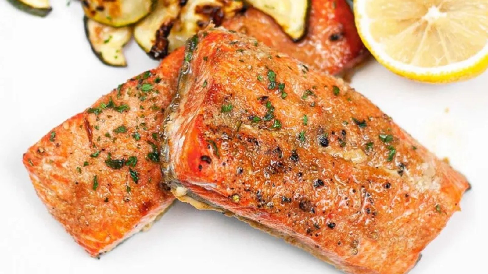Honey garlic salmon fillets glazed and served on a white plate with garnish.