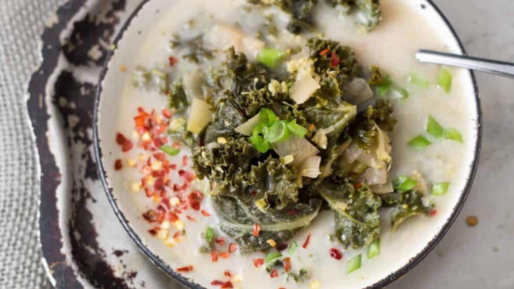 A bowl of green soup with small vegetable pieces visible on the surface.