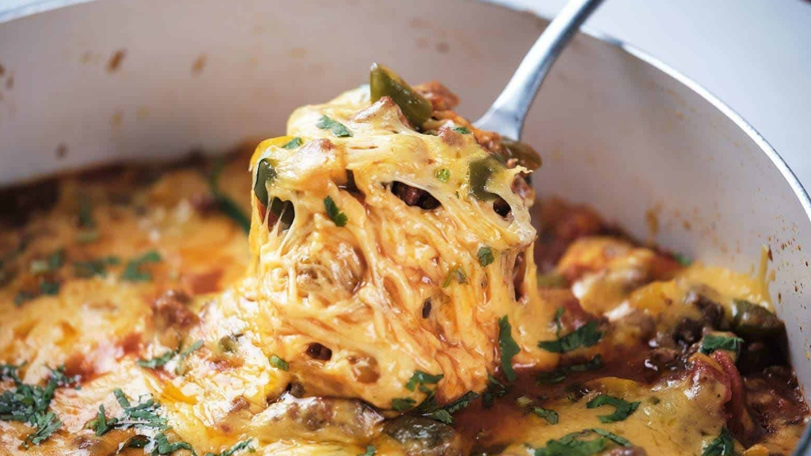 A close-up of ground beef taco skillet being served with a metal spoon.