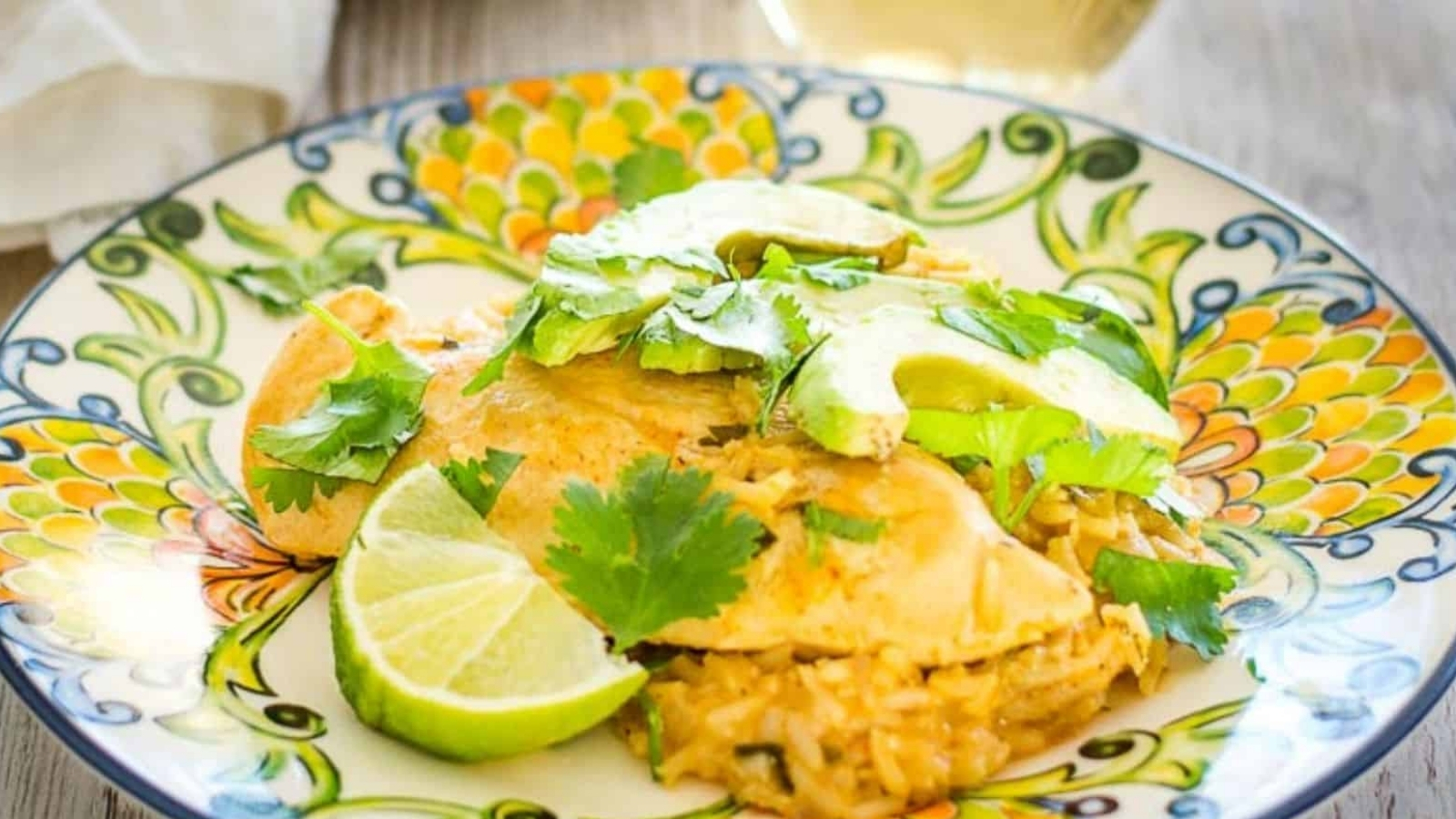 Cilantro lime chicken on a plate next to avocado and cilantro garnish.