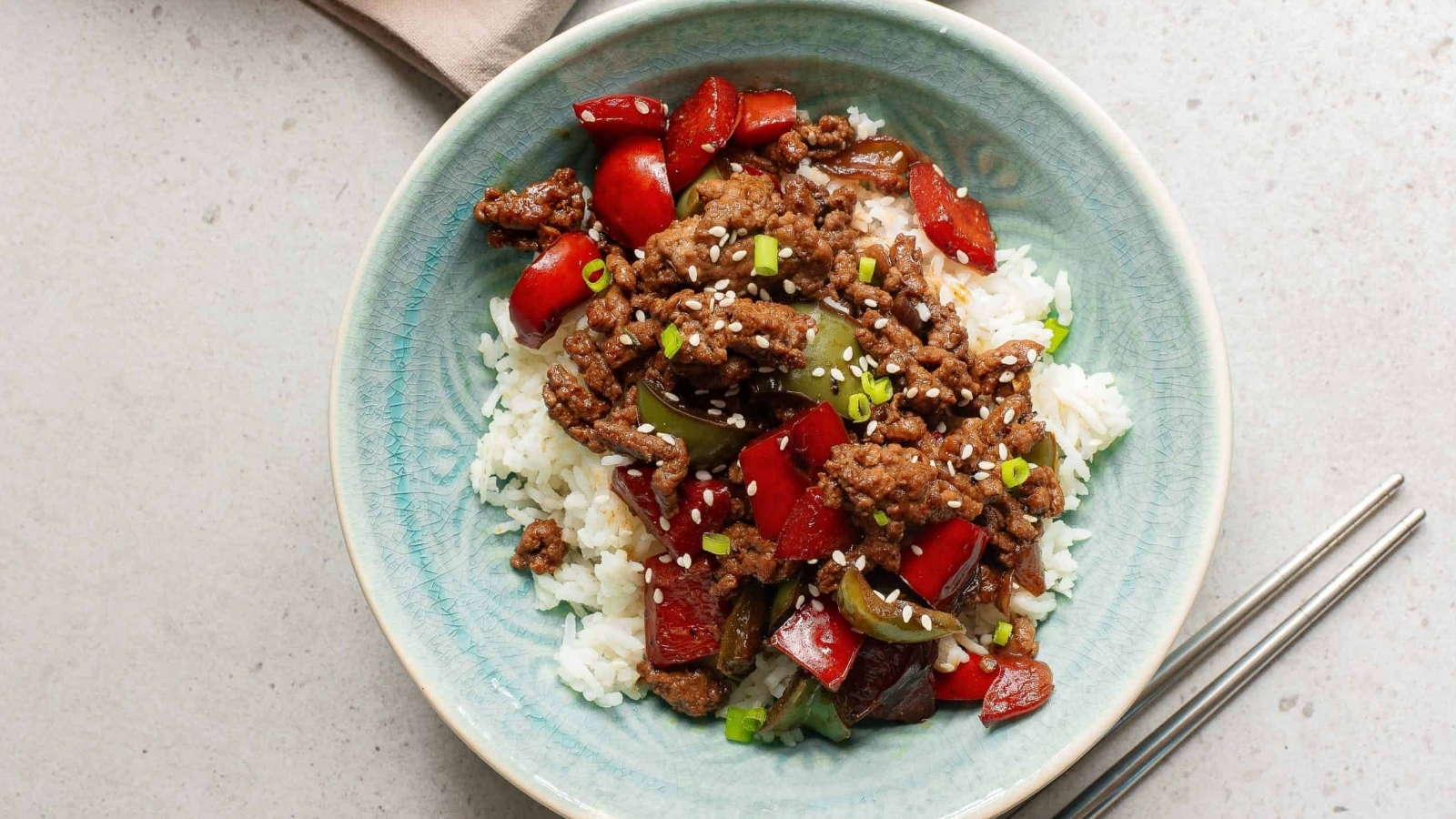 A bowl of beef stir fry with rice and peppers.