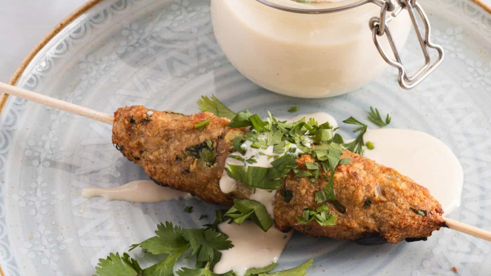 Chicken skewers on skewers with lemon wedges.