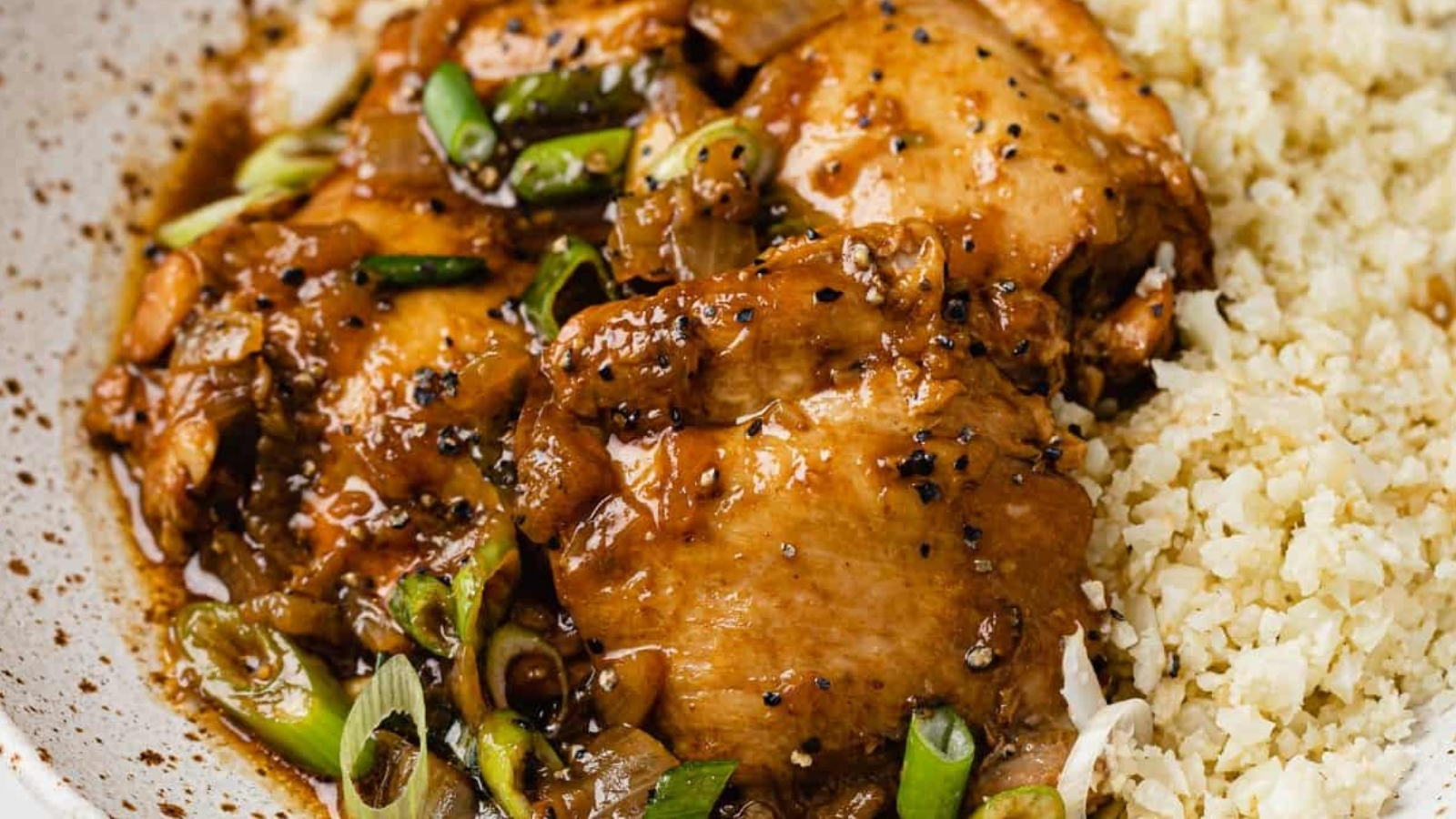 Instant pot chicken adobo in a bowl atop cauliflower rice.