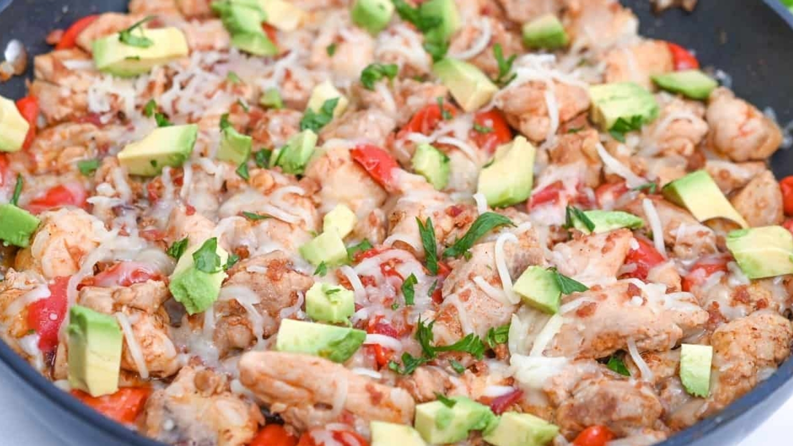 Chicken fajitas in a skillet with avocado.