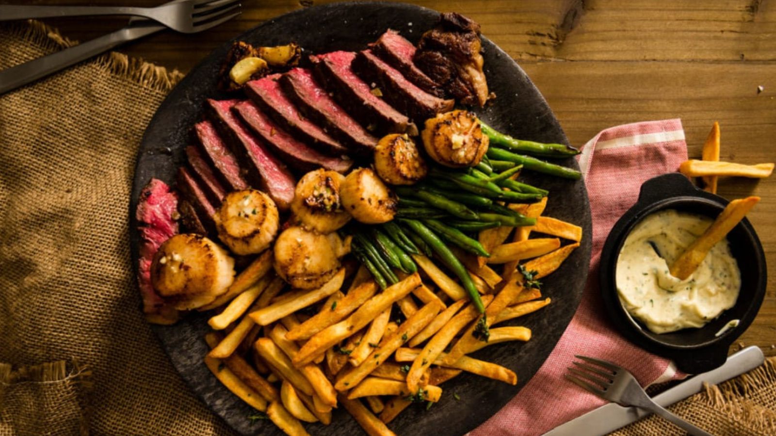 Strip steak and scallops seared together showing caramelized exterior on both.