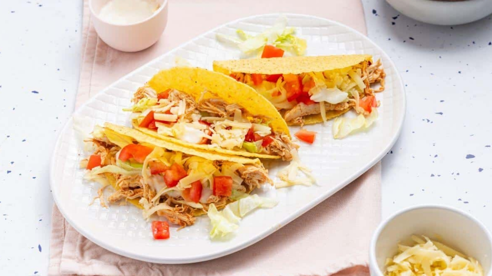 Two tacos on a plate with a bowl of guacamole.