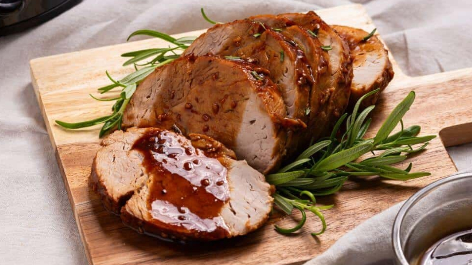 Pork tenderloin on a cutting board next to a slow cooker.
