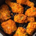 Seven pieces of crispy fried chicken with seasoning are arranged in the basket of an air fryer.