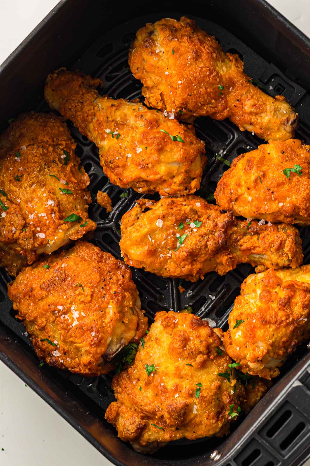 Seven pieces of crispy fried chicken with seasoning are arranged in the basket of an air fryer.