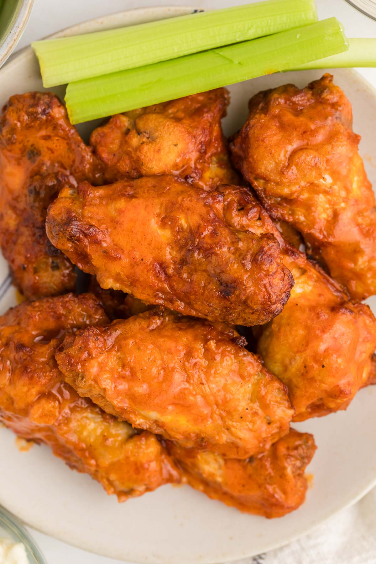 A plate of buffalo chicken wings with a side of celery sticks.