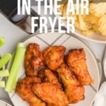 Plate of cooked chicken wings with celery sticks and potato chips, with text overlay reading "How to Cook Frozen Wings in the Air Fryer".