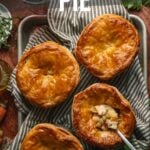 Overhead view of four individual lobster pot pies on a striped towel, with one partially eaten, revealing the filling. Text overlay reads, “How to make lobster pot pie.”.