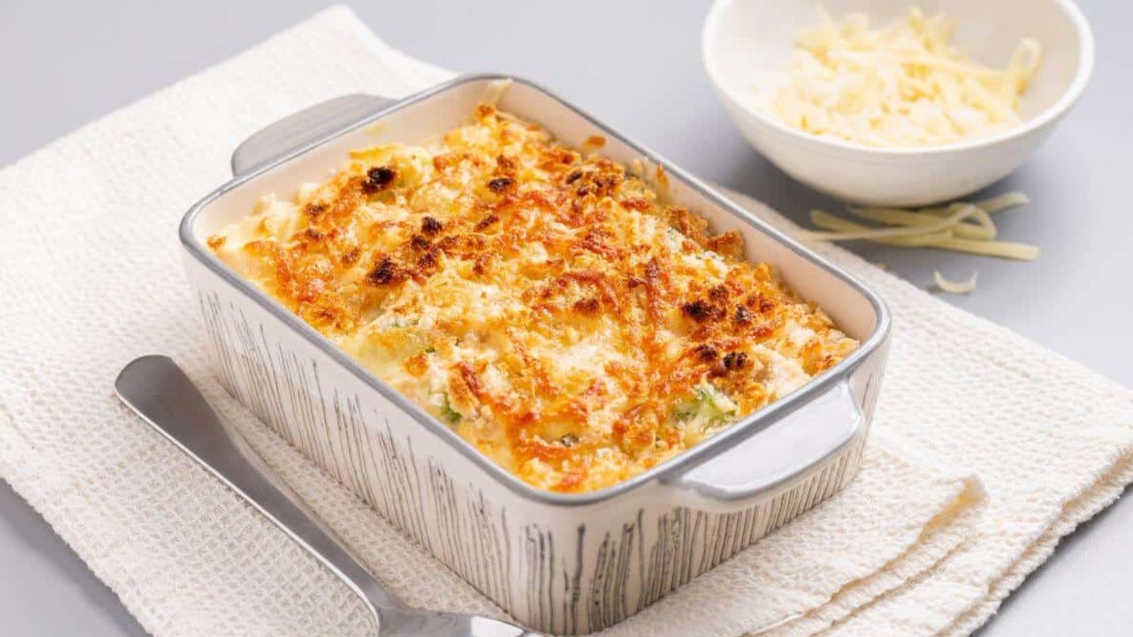 A casserole dish with cheese and broccoli on a napkin.