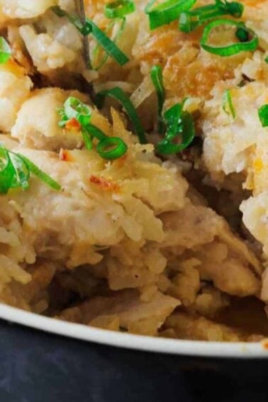 A vintage meal classic—a baked casserole topped with shredded potatoes and sliced green onions, with a portion removed to reveal the creamy filling inside.