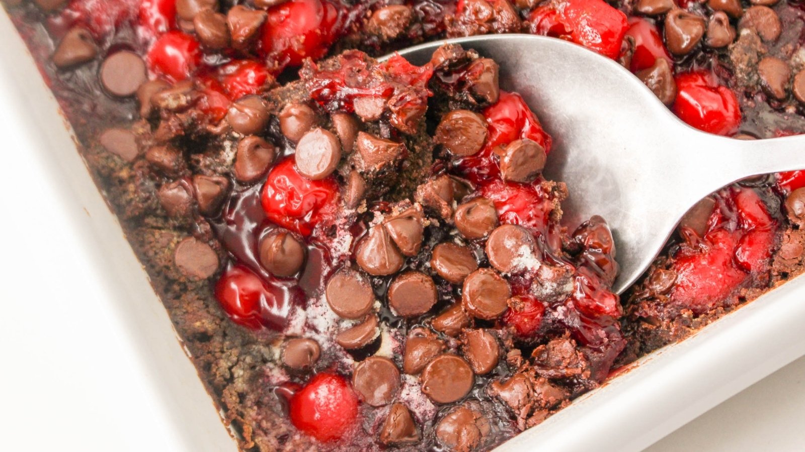 A dish with chocolate chips and cherries in it.