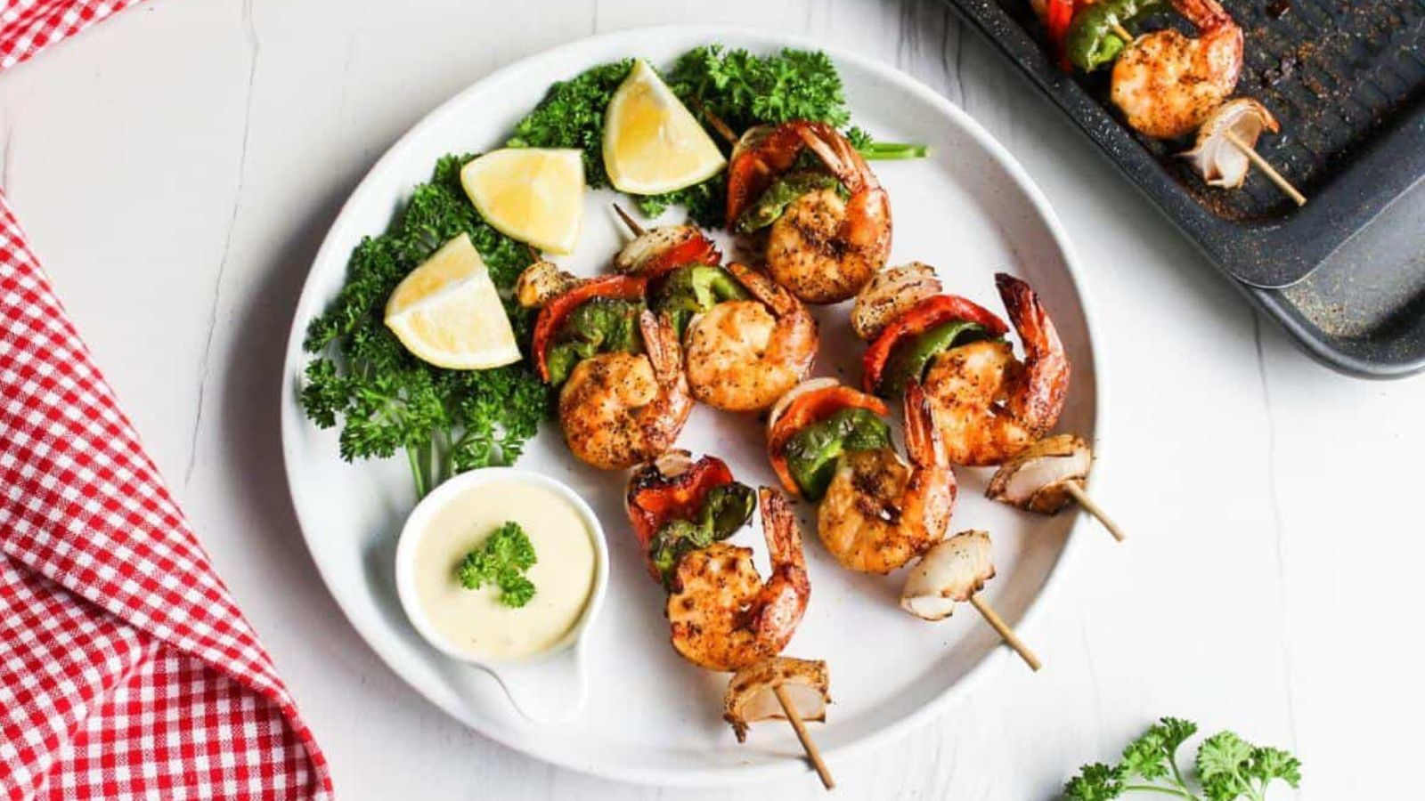 Shrimp skewers on a plate with lemon wedges.