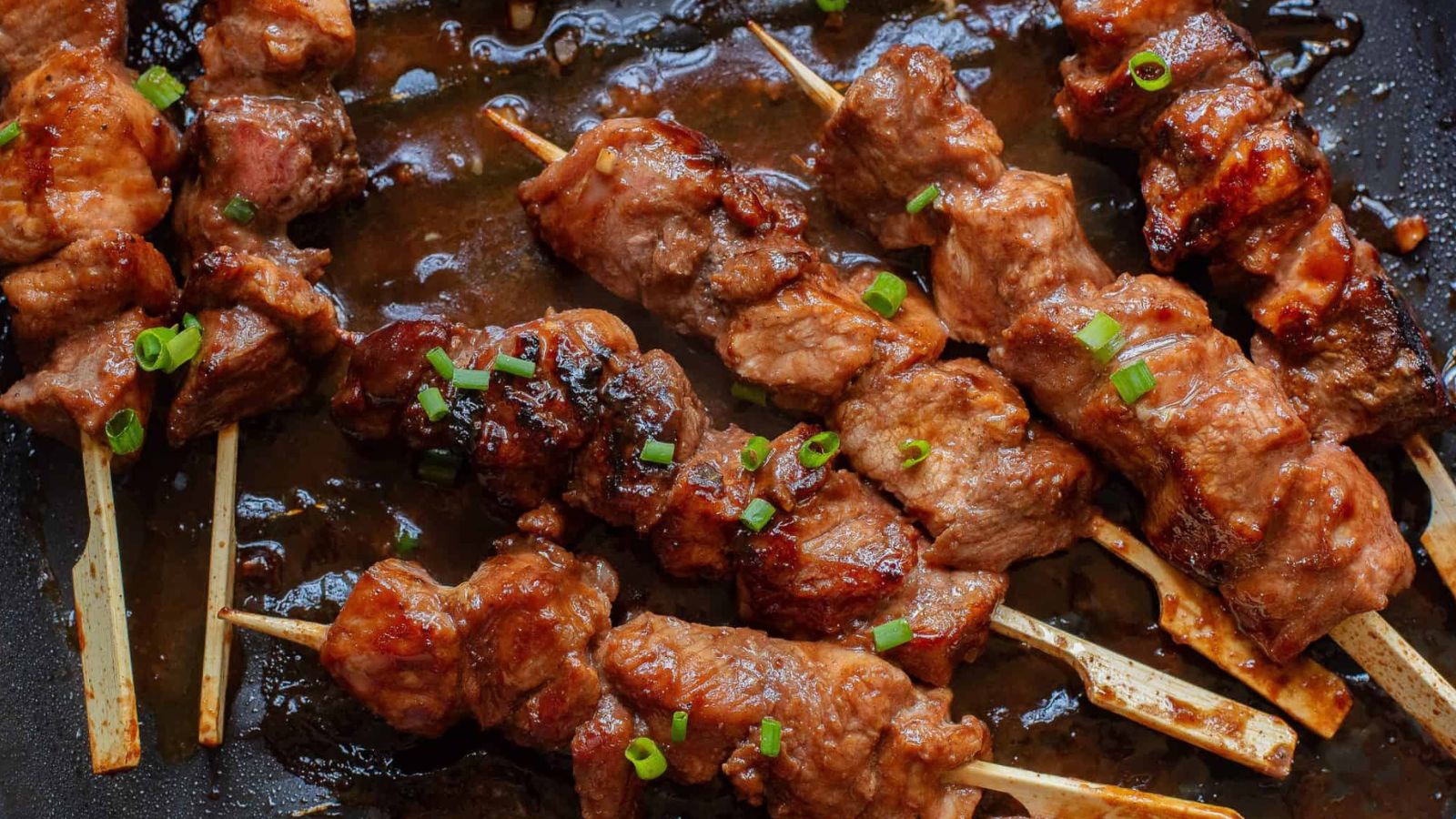 Hoisin Pork Tenderloin on skewers in a pan.