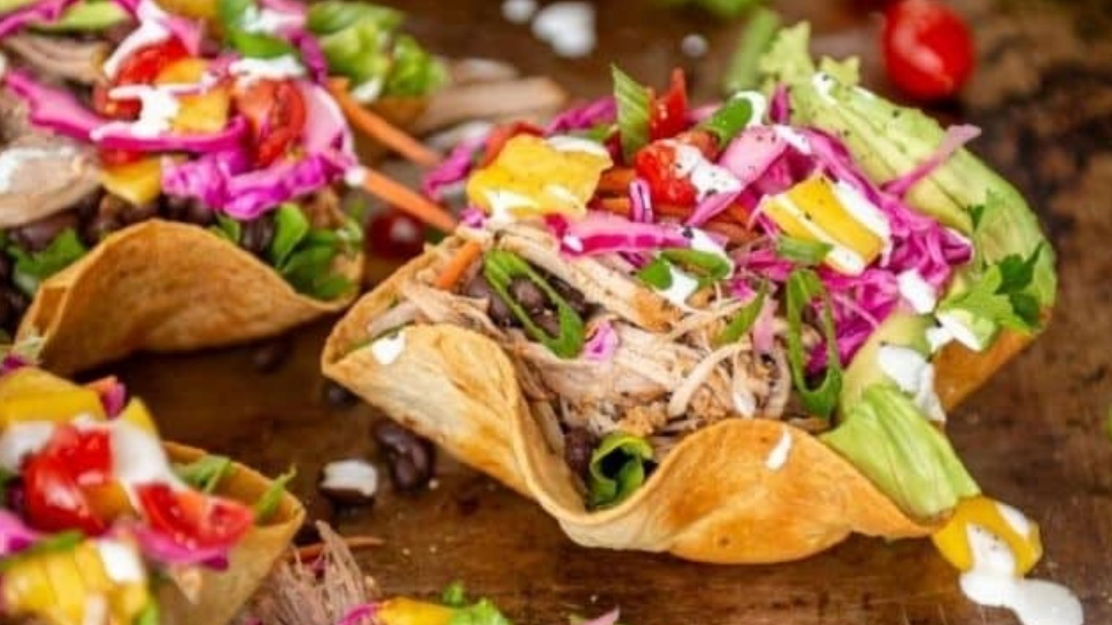 Carnita bowls filled with shredded pork, rice, beans, and toppings layered warmly from the Instant Pot.