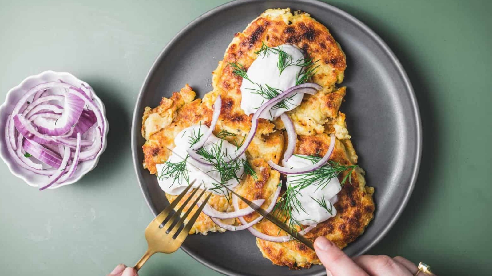 Irish boxy potato pancakes on a plate, and sliced onions in a small bowl beside them.