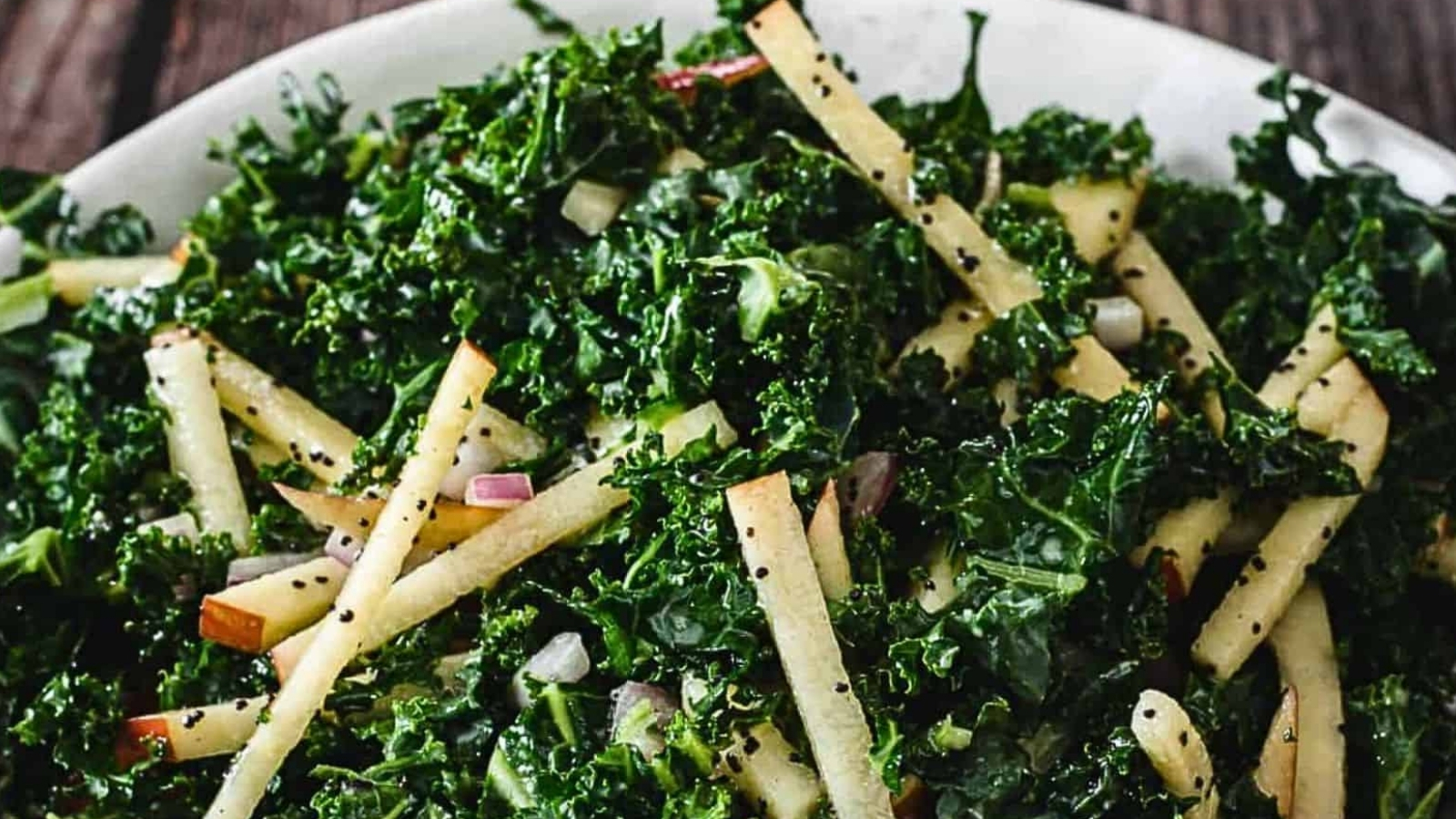 A bowl of kale salad on a wooden table.
