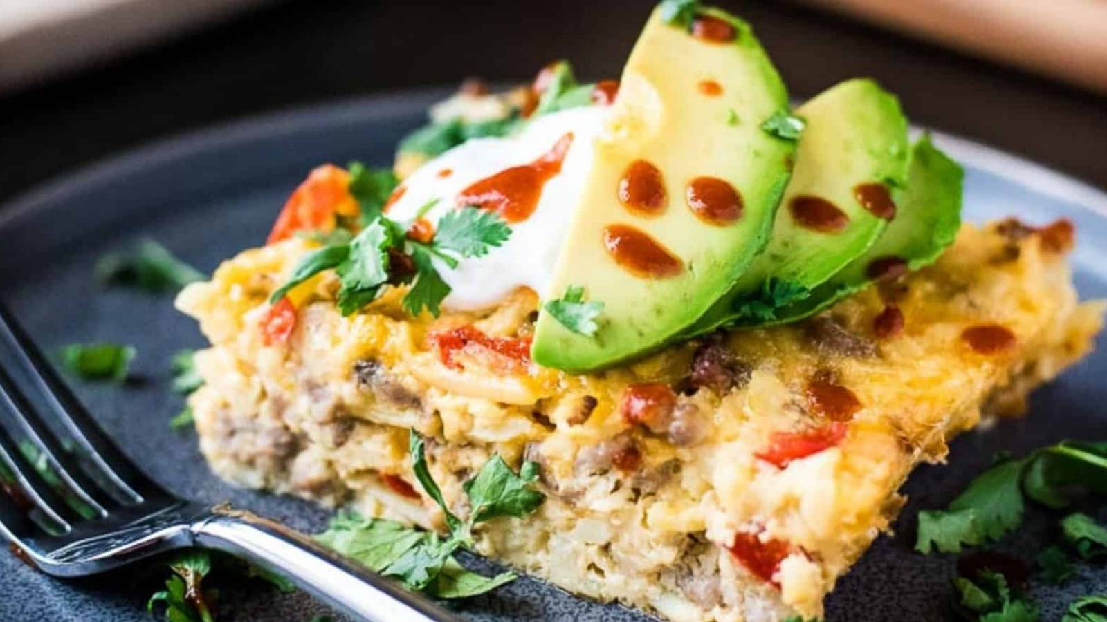 An overhead shot of breakfast casserole next to a single serving and a toppings bar.